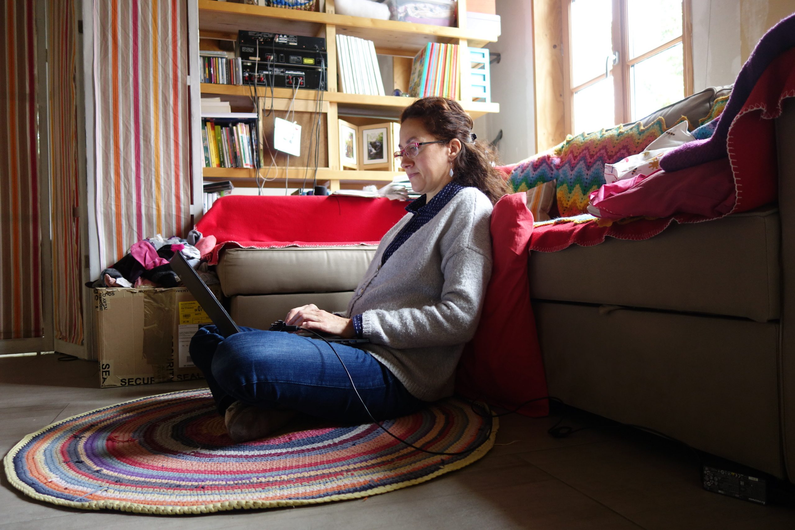 femme en télétravail assise au sol adossée au canapé