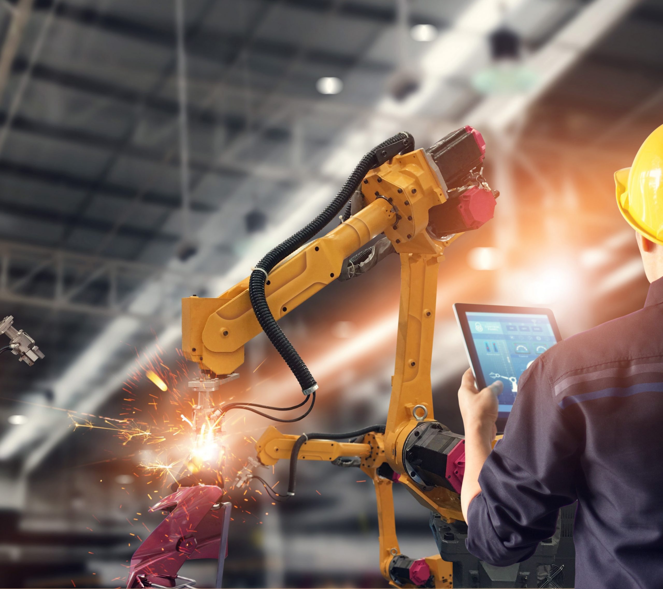 Robot monitoré par un ingénieur via une tablette. AdobeStock - Ipopbaand control automation robot arms machine in intelligent factory industrial on monitoring system software. Welding robotics and digital manufacturing operation.