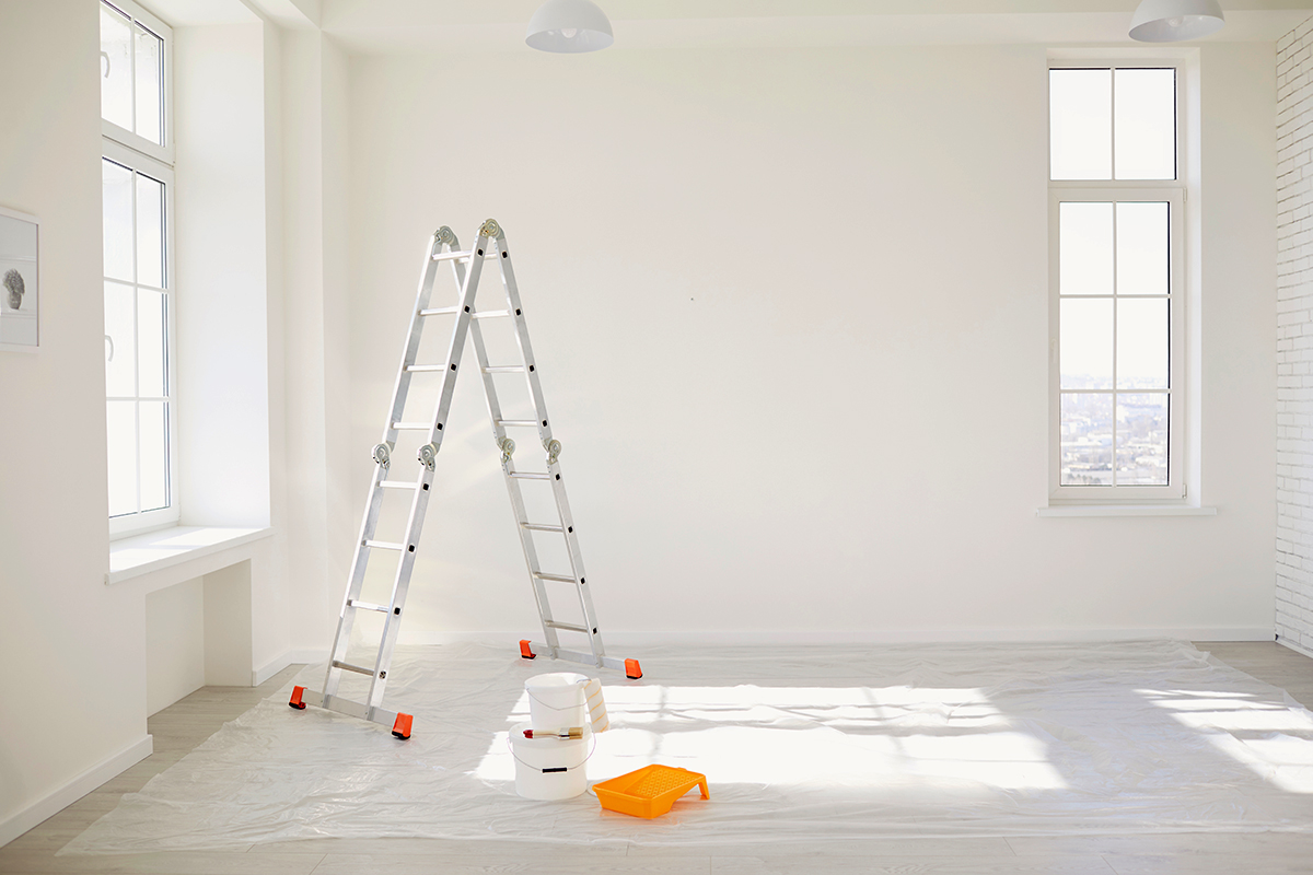 Painting in a white room with windows with a stepladder - Crédit: Studio Romantic/AdobeStock