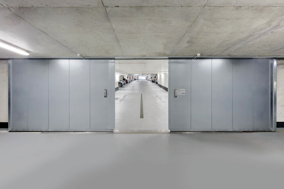 Porte coupe-feu coulissante installée dans un parking – Crédit: Novoferm Lutermax Porte coupe-feu coulissante installée dans un parking - Crédit: Novoferm Lutermax