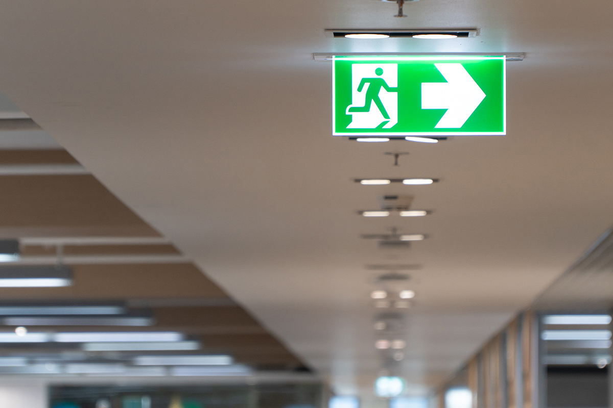 Green fire escape sign hang on the ceiling in the office - Crédit: Prot/AdobeStock