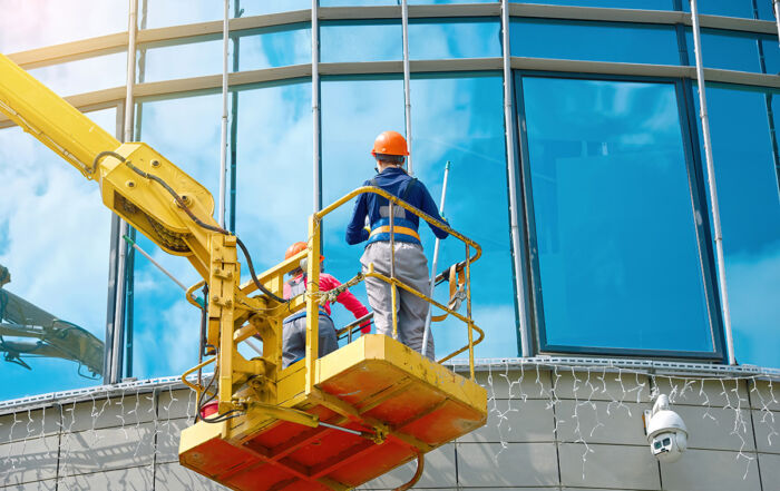 Window washing on high-rise office building in crane bucket - Crédit: Tricky Shark/AdobeStock