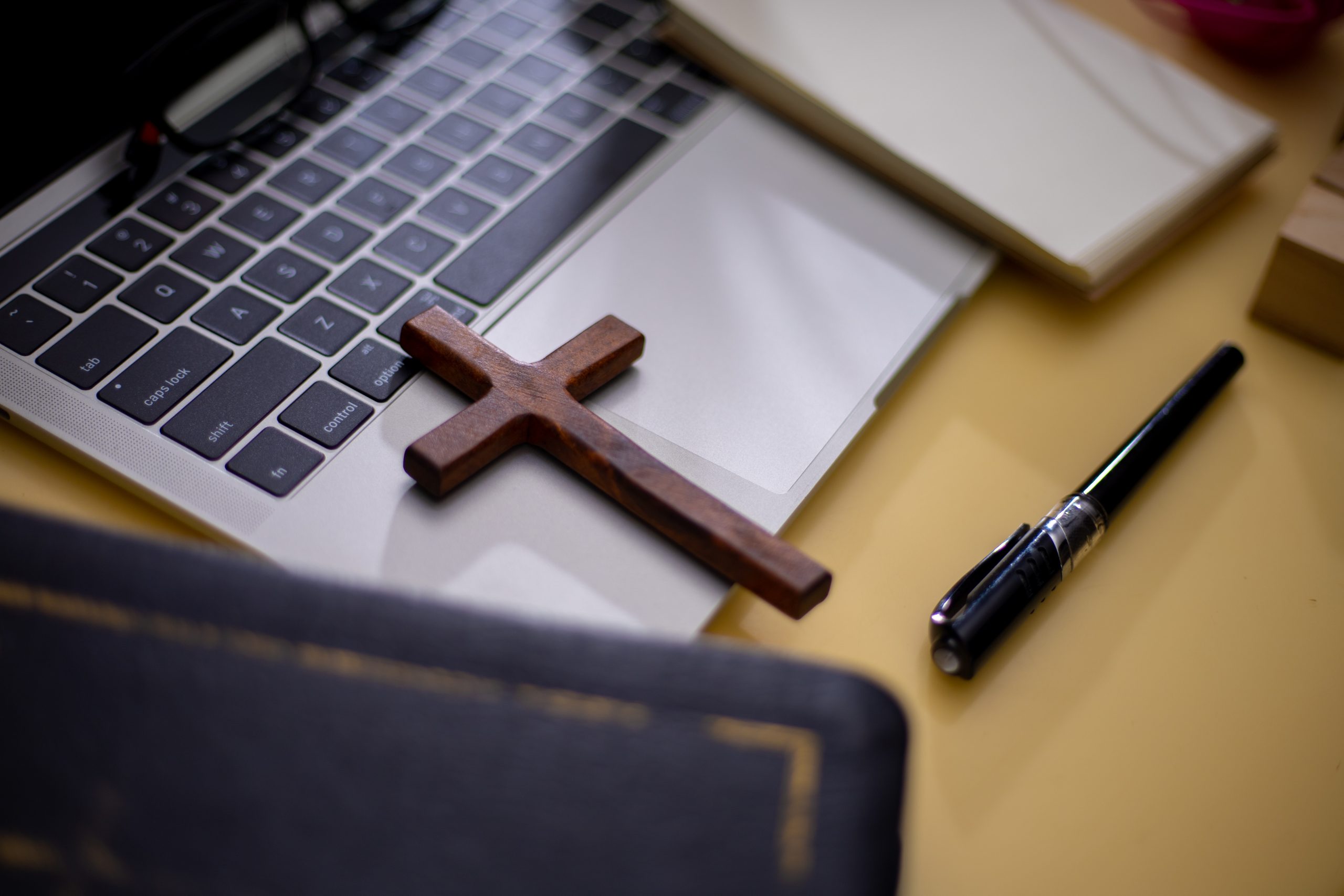 Cross on bible with headset and laptop in online study bible concept- Crédit: Sticker2you/AdobeStock