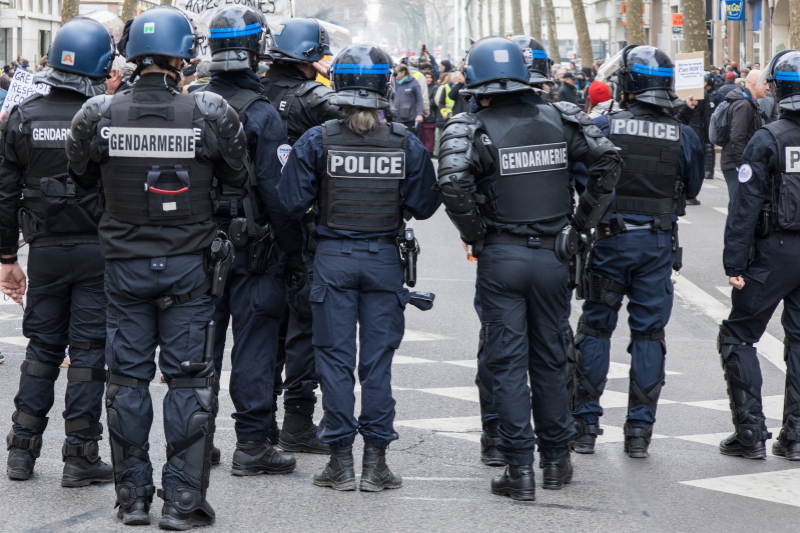 Photo d'une équipe de gendarmes et de policiers nationaux, de dos, en intervention lors d'une manifestation.
