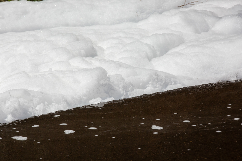 Une épaisse mousse contenant des Pfas retenue sur un cours d'eau.