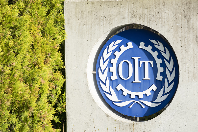 Le logo de l’OIT – Organisation internationale du travail – sur un mur du siège à Genève (Suisse) © Hectorchristiaen-Adobestock