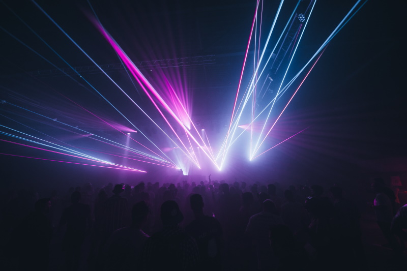 Jeux de lasers dans un ERP. Crédit : ac3ju/AdobeStock Foule dans le noir devant un spectacle avec lasers.